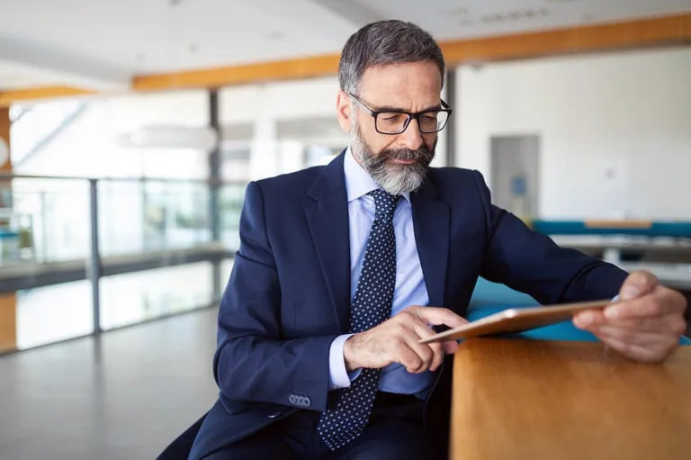 Man in suit sat looking at iPad