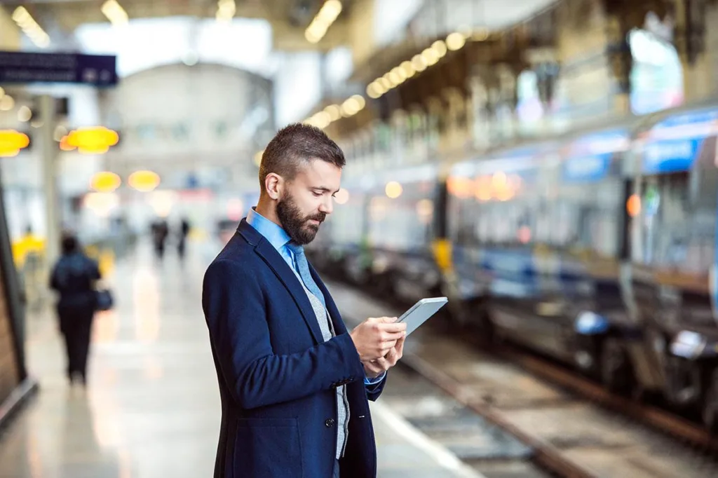 Man standing at train station with iPad